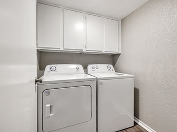 a washer and dryer in an empty laundry room with white cabinets at Diamond Ridge Townhomes, Oklahoma City